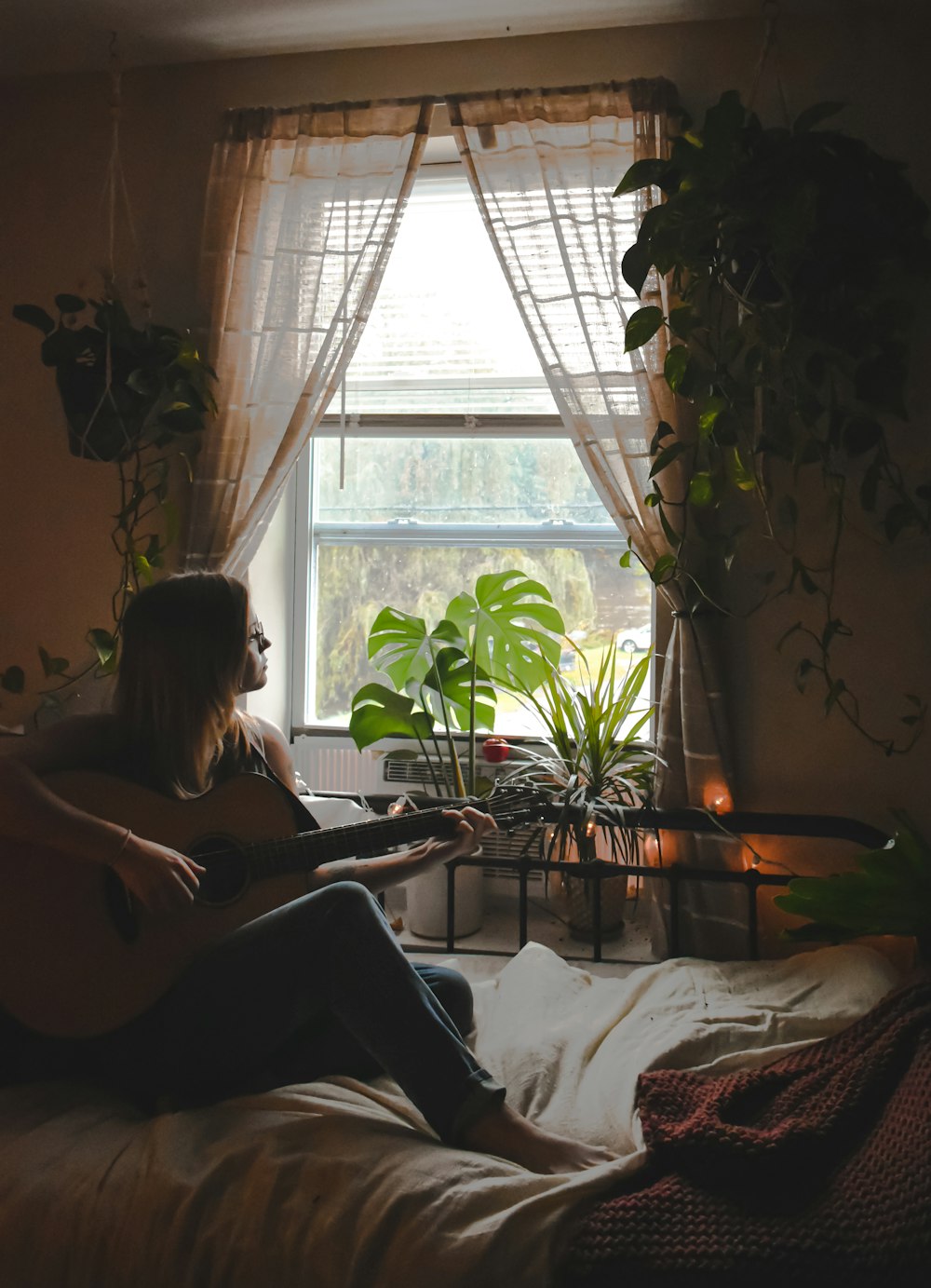a woman sitting on a bed playing a guitar