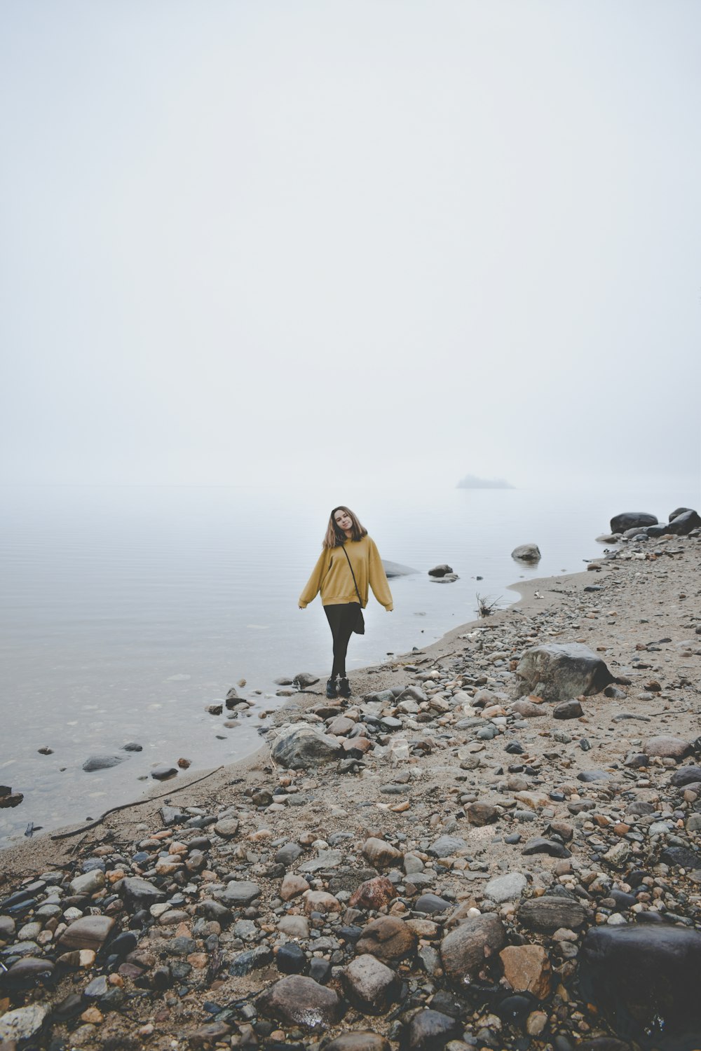 a woman standing on a rocky beach next to the ocean