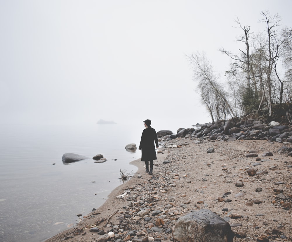 a man standing on top of a rocky beach next to the ocean