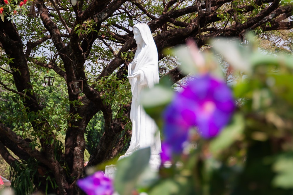 a white statue sitting in the middle of a forest