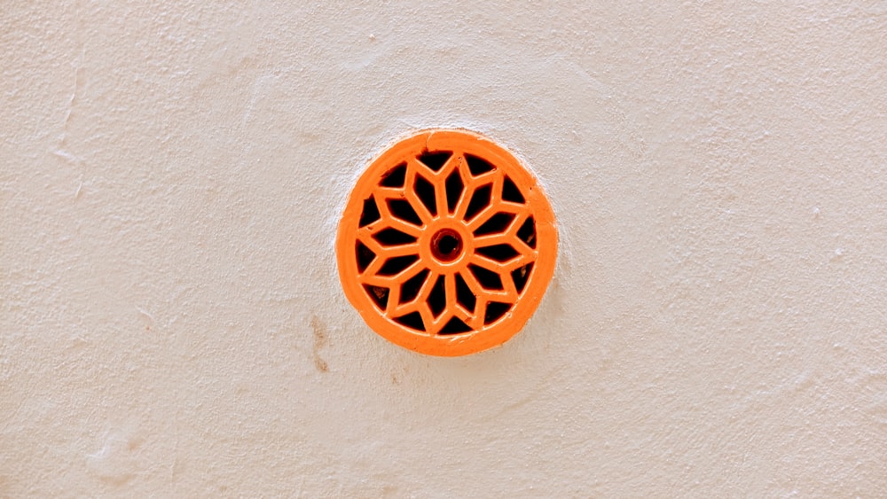 Un objeto naranja redondo en una pared blanca