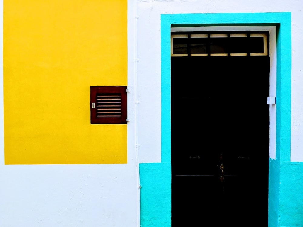 a yellow and blue building with a black door