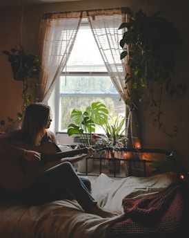 A student smiling while playing an acoustic guitar in a cozy music room.