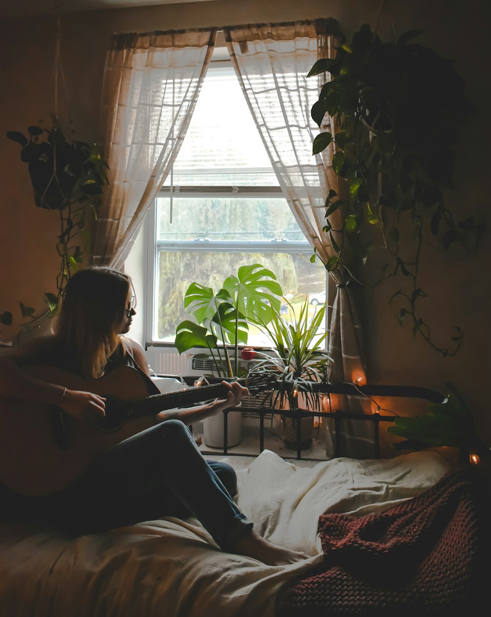 a woman sitting on a bed playing a guitar