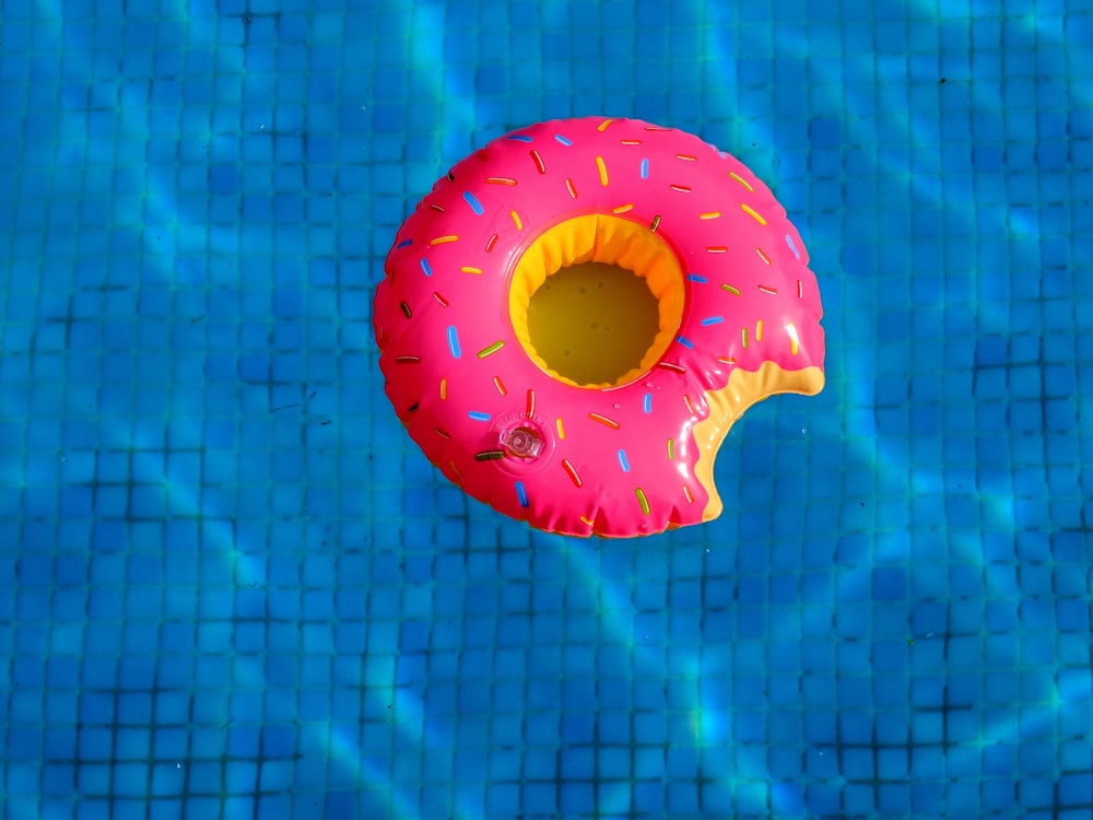 a pink donut floating on top of a blue swimming pool