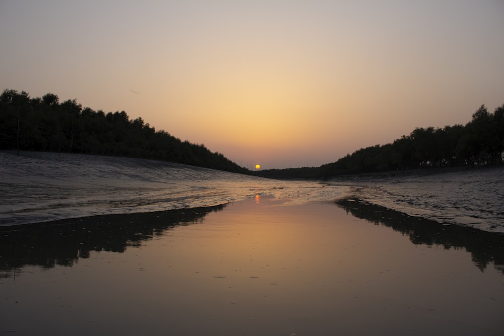 the sun is setting over the water at the beach