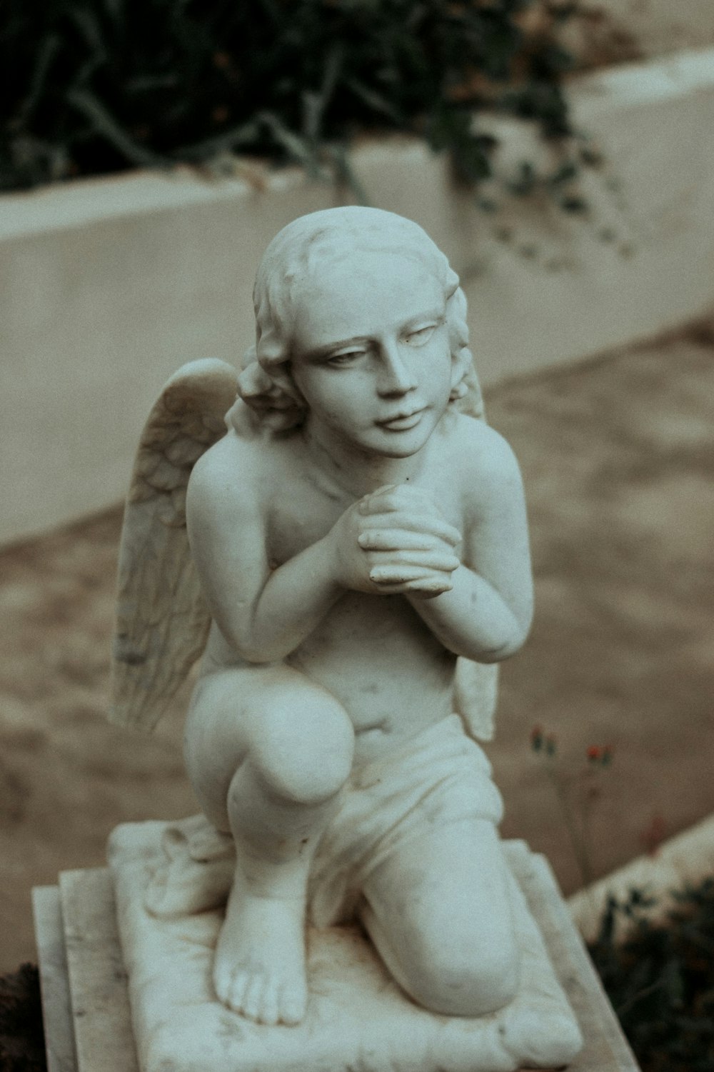 una estatua de un ángel arrodillado sosteniendo una cruz