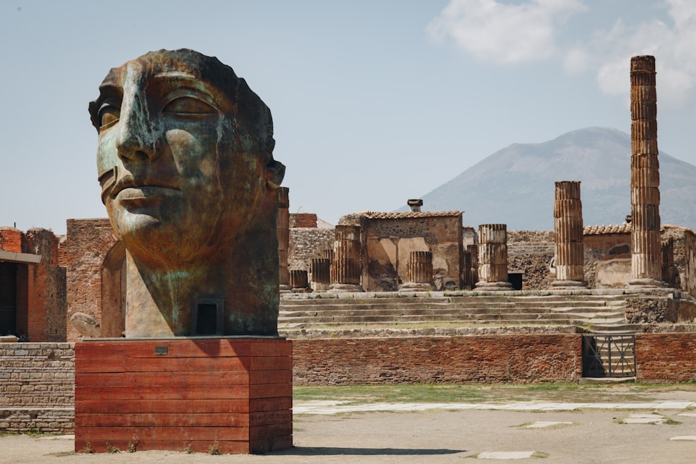 Une statue de la tête d’une femme devant les ruines