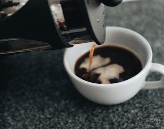 a cup of coffee being poured into it