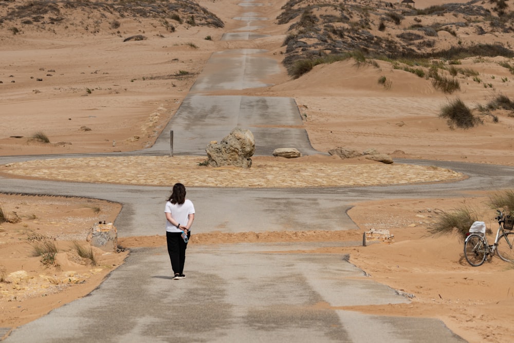 a woman walking down a road in the desert