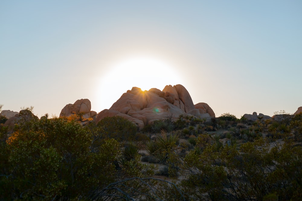 the sun is setting behind a rocky outcropping