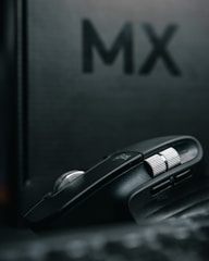 A close-up shot of a sleek mouse racing down a tiny track with blurred cheering crowd in the background.