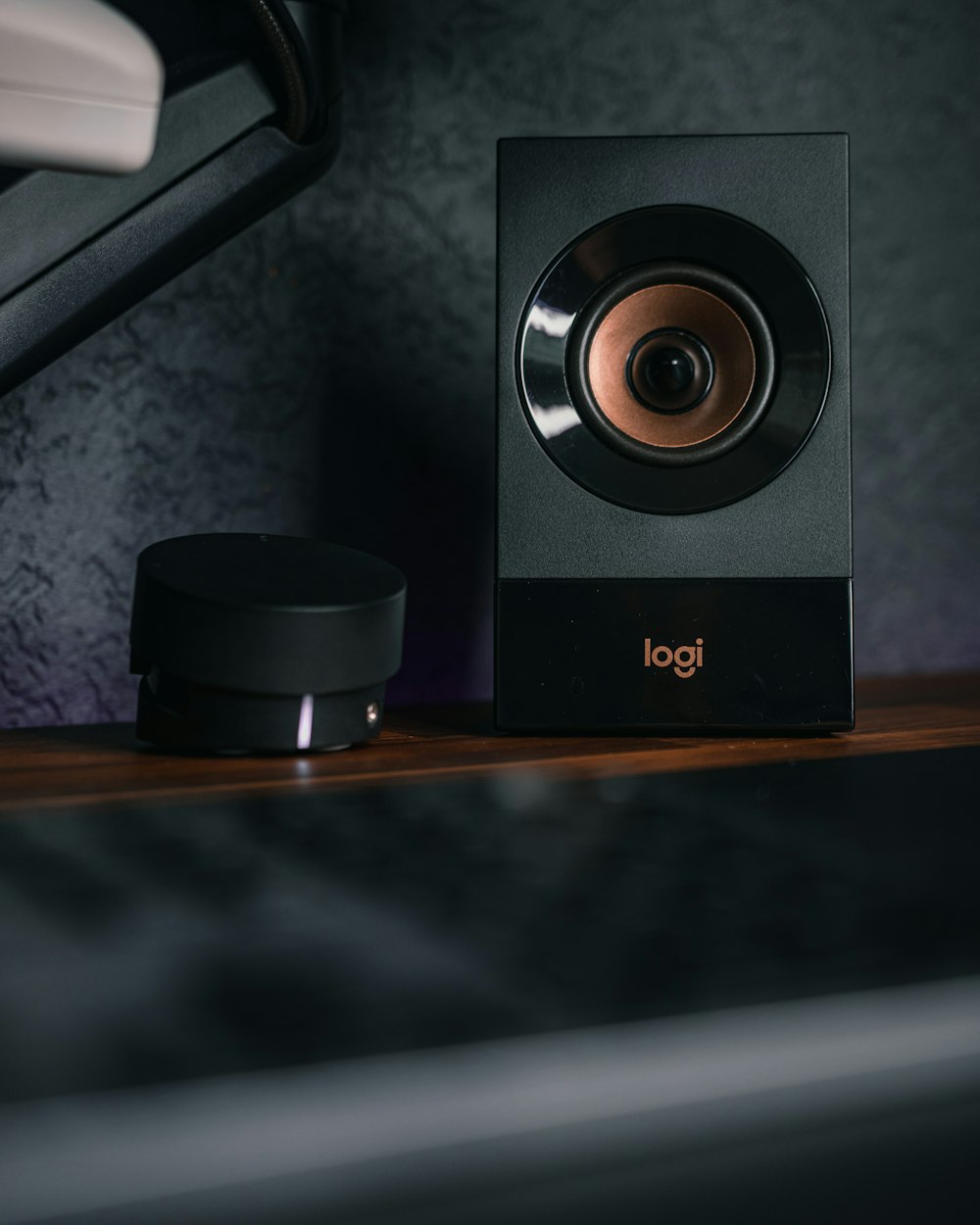 a black speaker sitting on top of a wooden shelf