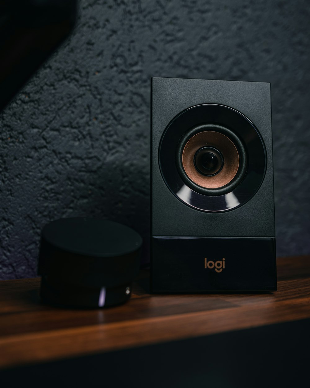 a black speaker sitting on top of a wooden table