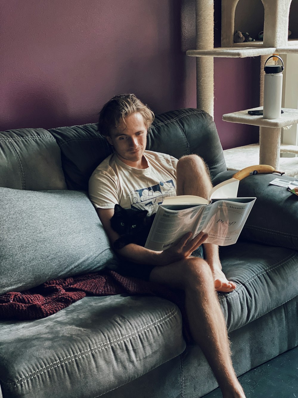 a man sitting on a couch reading a book