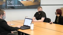 a group of people sitting around a table with a laptop