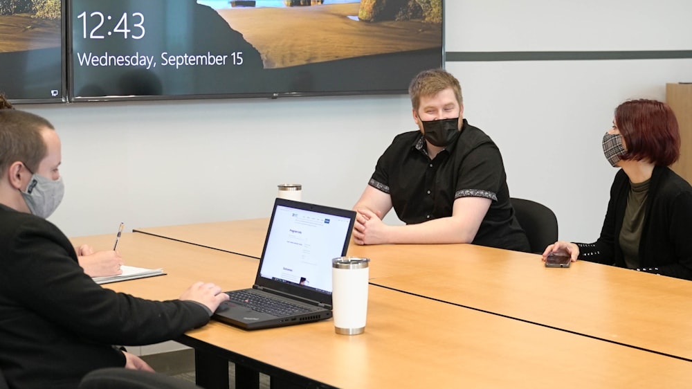 un groupe de personnes assises autour d’une table avec un ordinateur portable