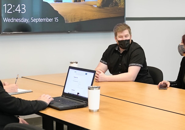 a group of people sitting around a table with a laptop