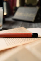 a red pen sitting on top of an open book