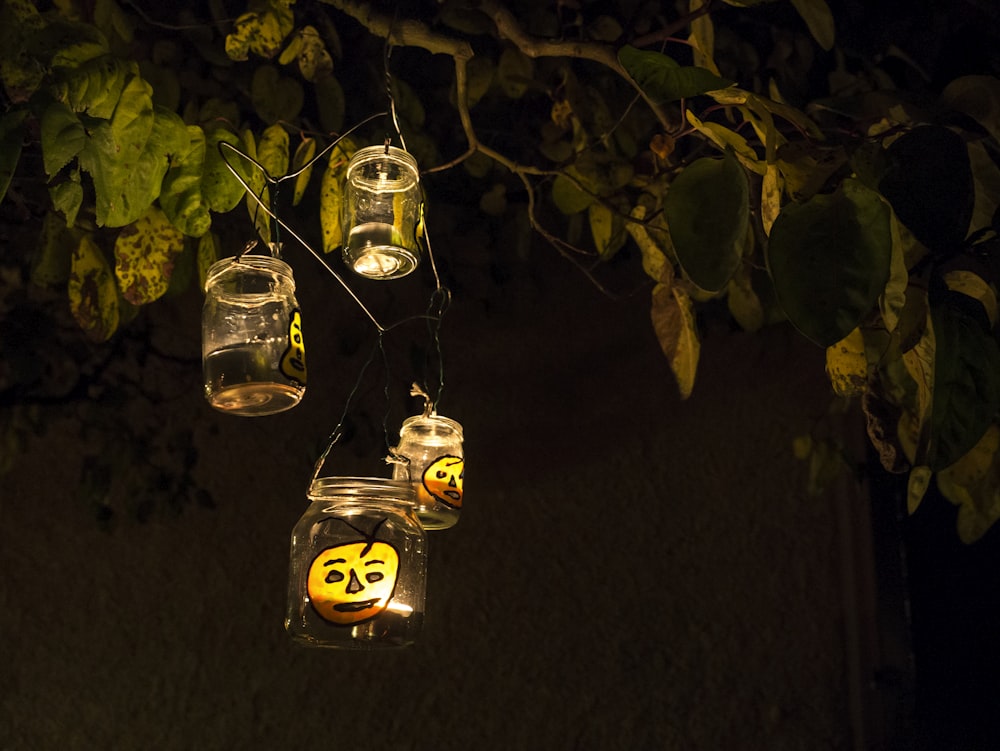 a group of mason jars hanging from a tree