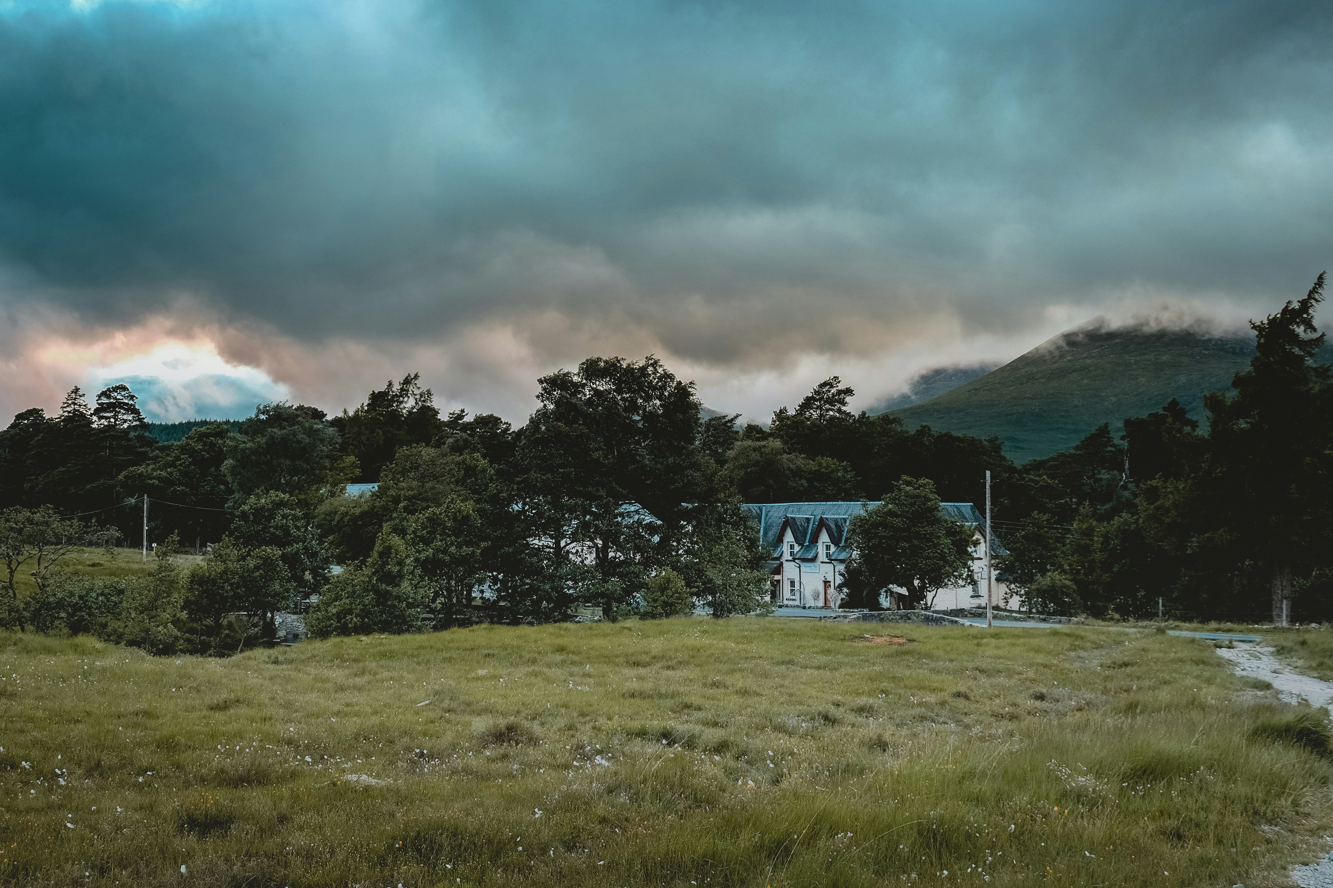 a house in the middle of a field with mountains in the background