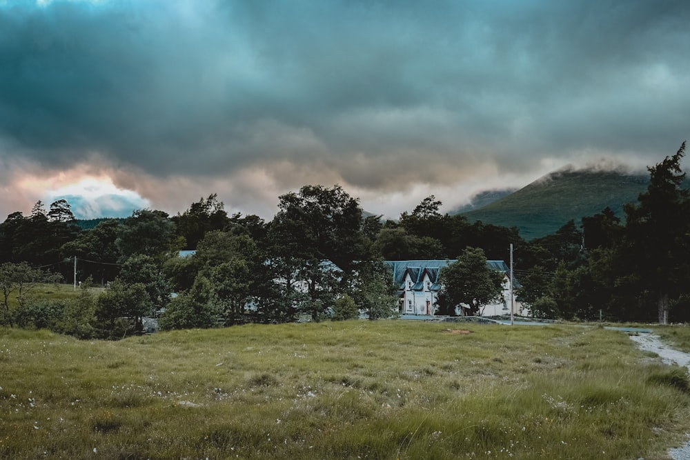 a house in the middle of a field with mountains in the background