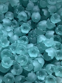 Translucent, teal-colored plastic flowers are scattered closely together, creating a textured, overlapping pattern.