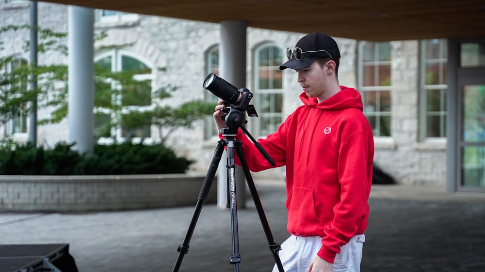 a man in a red hoodie taking a picture with a camera