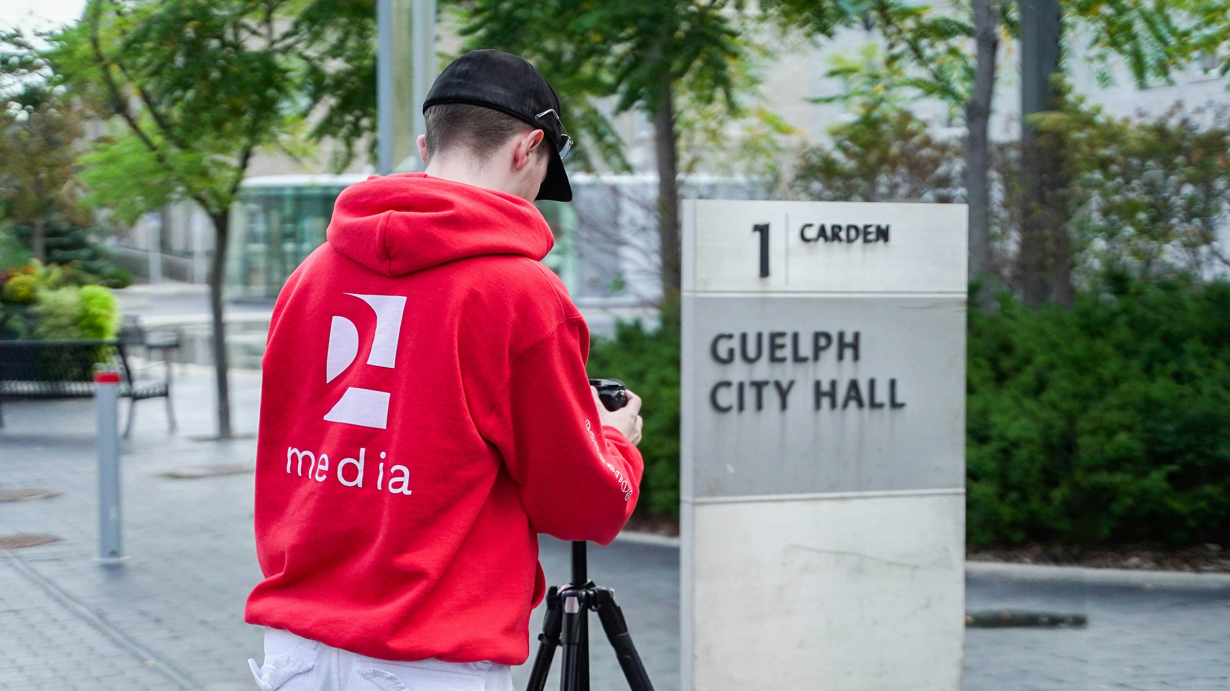 a man in a red hoodie taking a picture of a sign