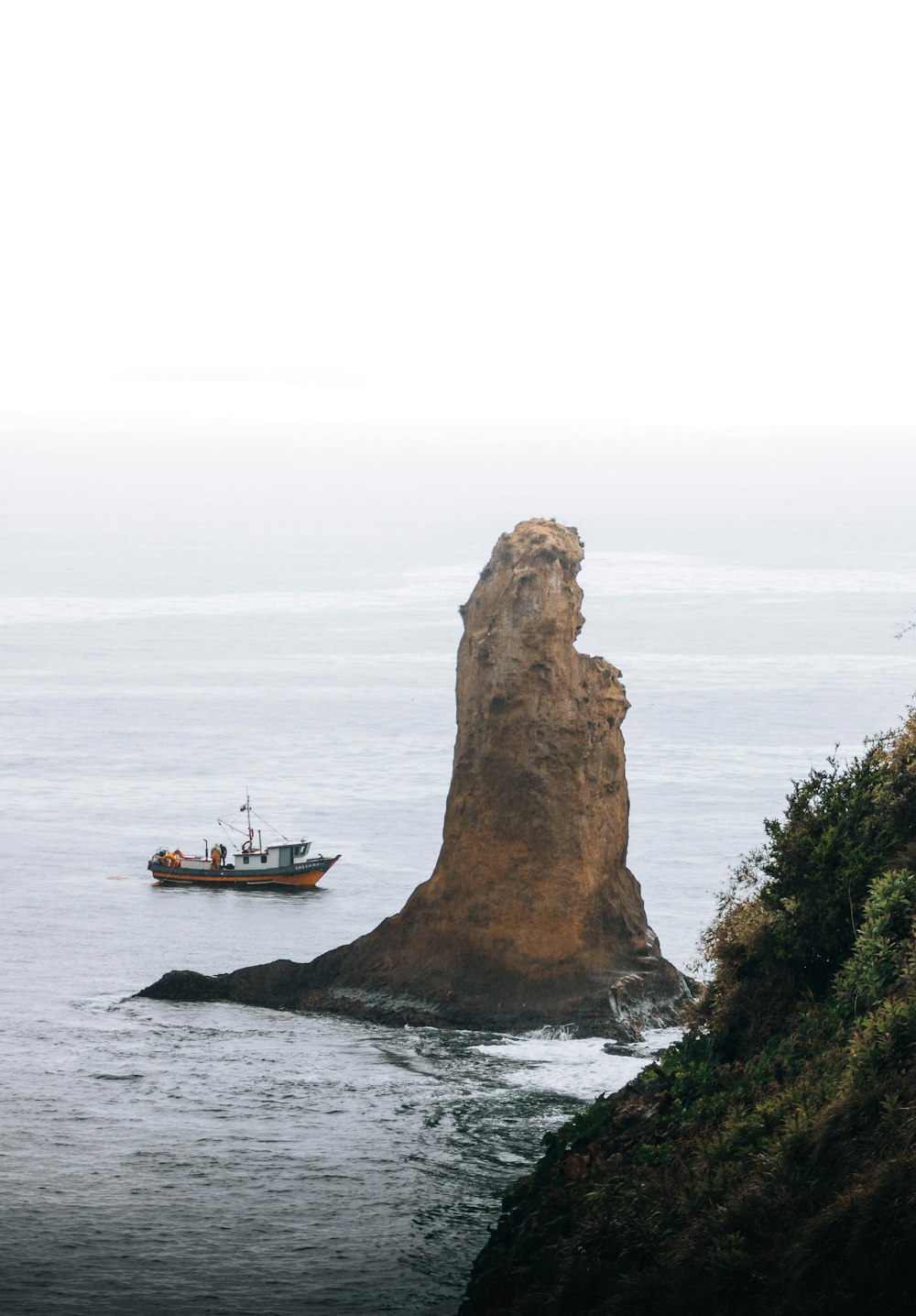 a boat in the water near a large rock