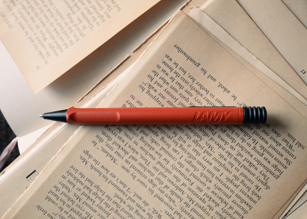 a red pen sitting on top of an open book