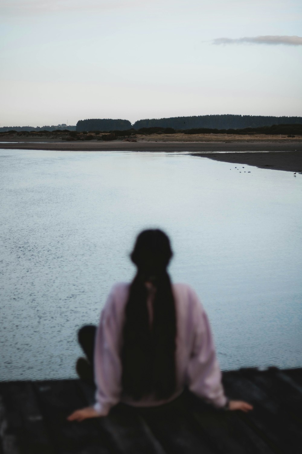 a person sitting on a dock looking at a body of water