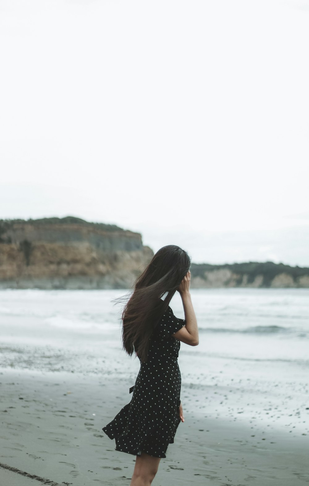 a woman standing on top of a beach next to the ocean