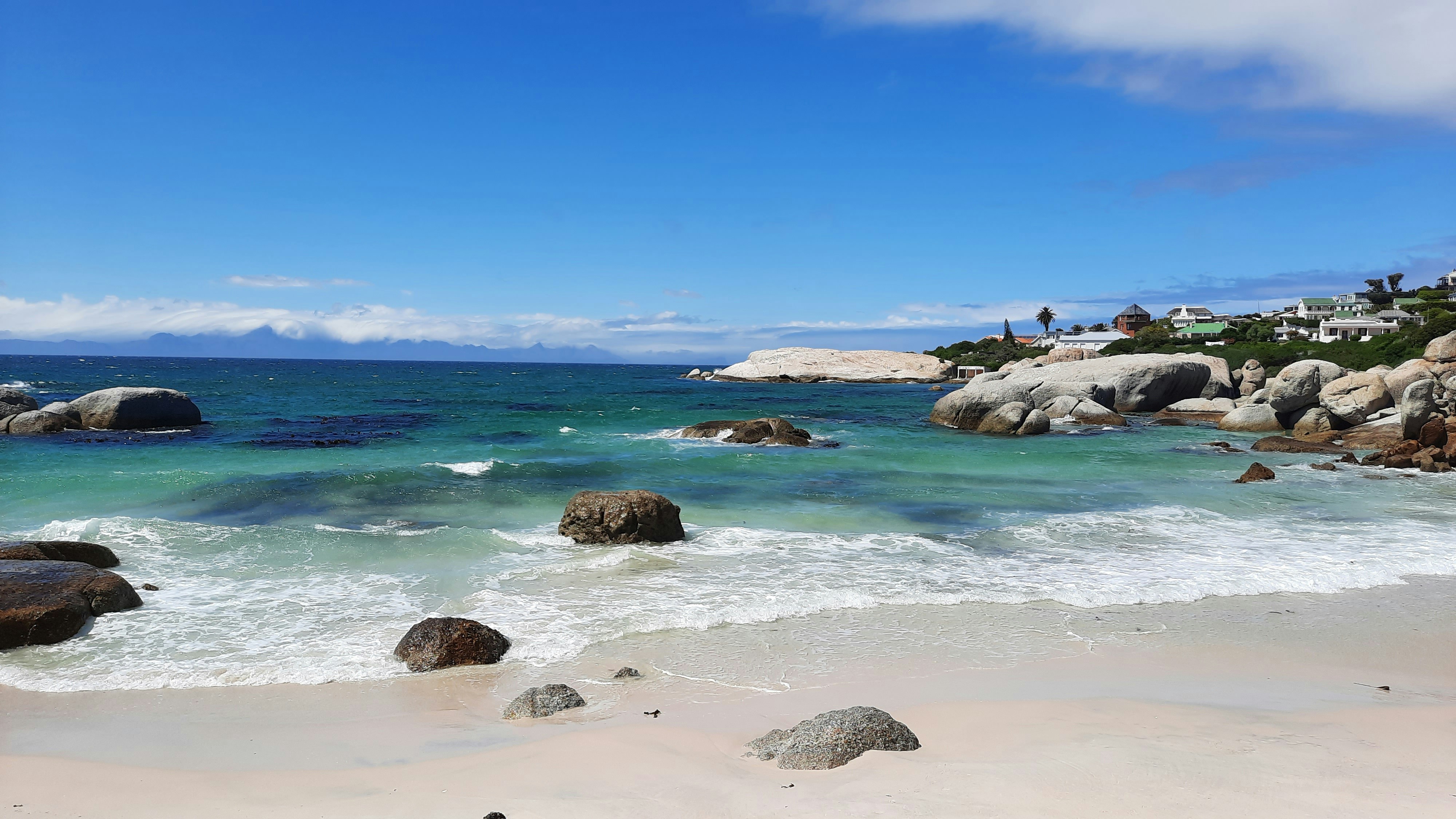a beach with rocks and clear blue water