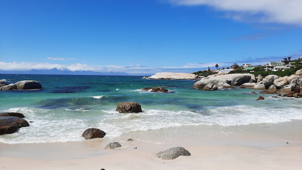 a beach with rocks and clear blue water