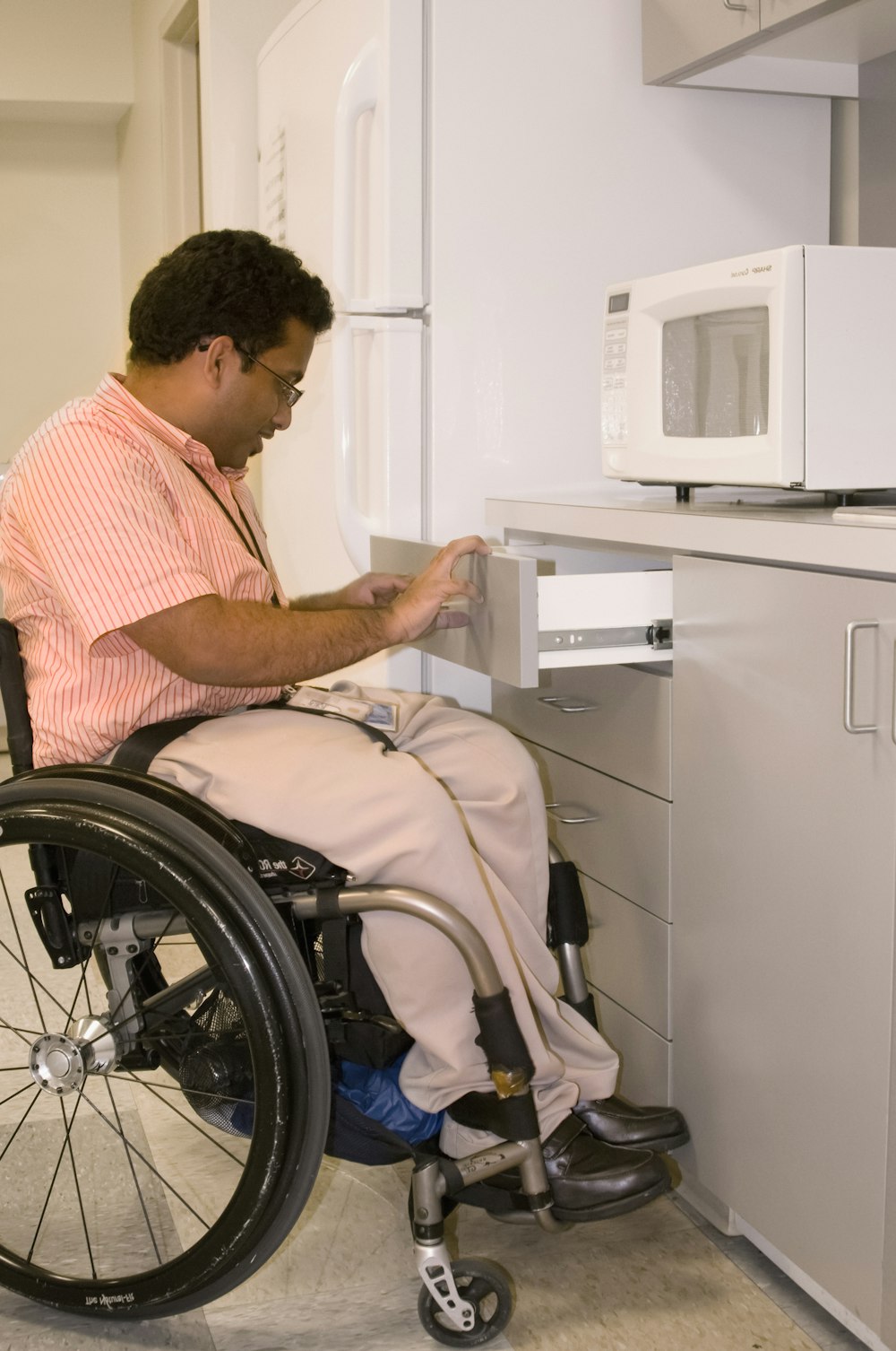 um homem em uma cadeira de rodas usando um micro-ondas