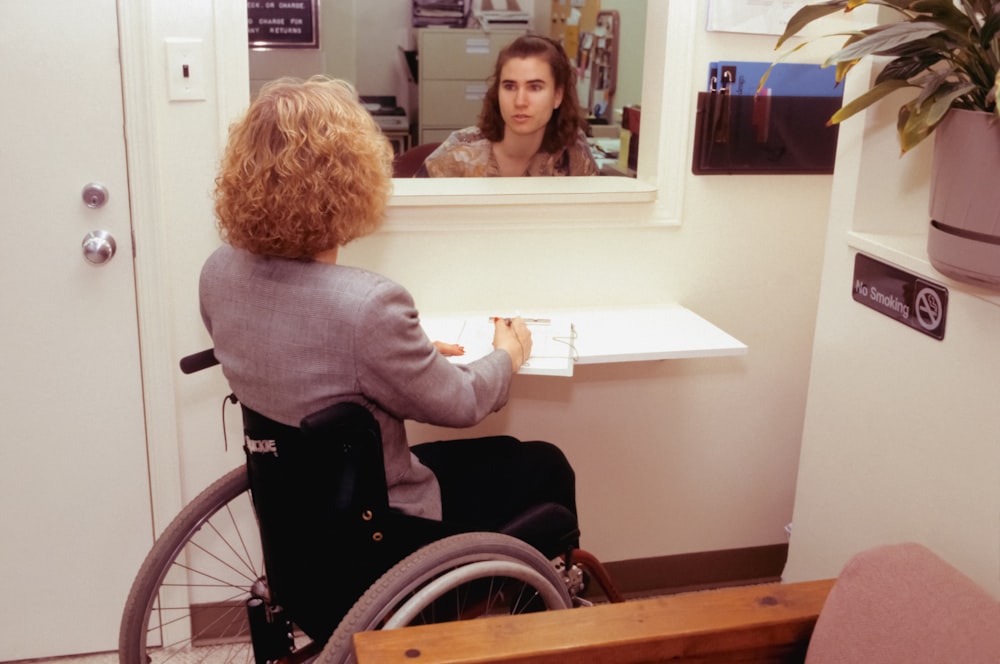 a woman sitting in a wheel chair in front of a mirror