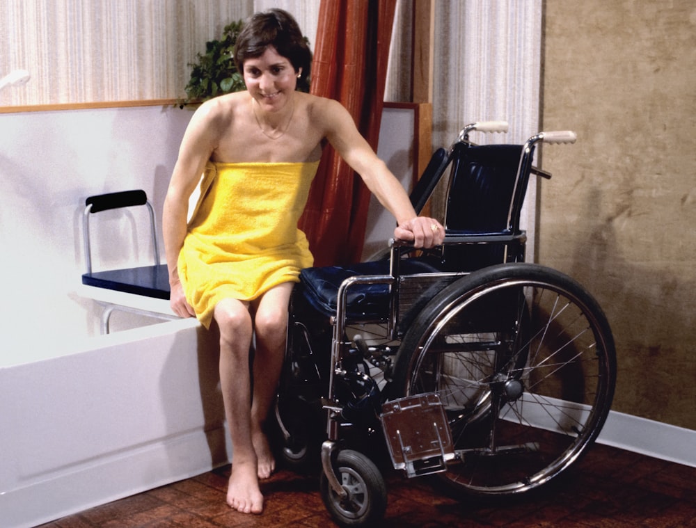 uma mulher em uma toalha amarela sentada em uma cadeira de rodas