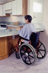 a woman in a wheel chair in a kitchen