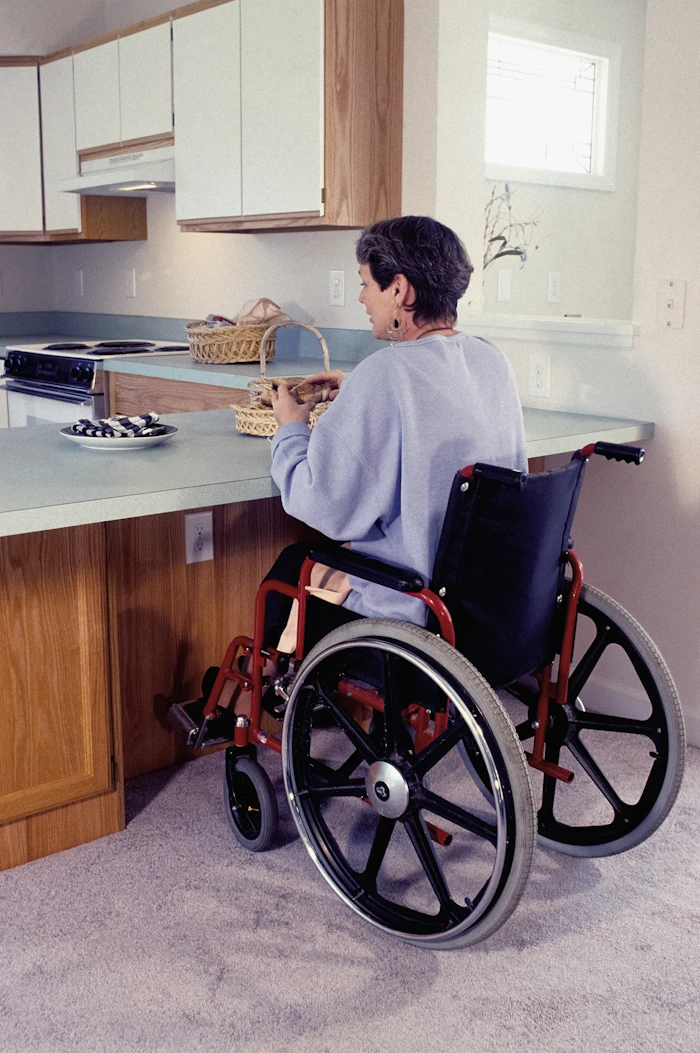 A woman using a wheelchair preparing food at her kitchen bench