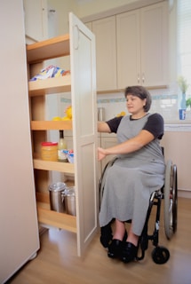 a woman in a wheel chair opening a cabinet