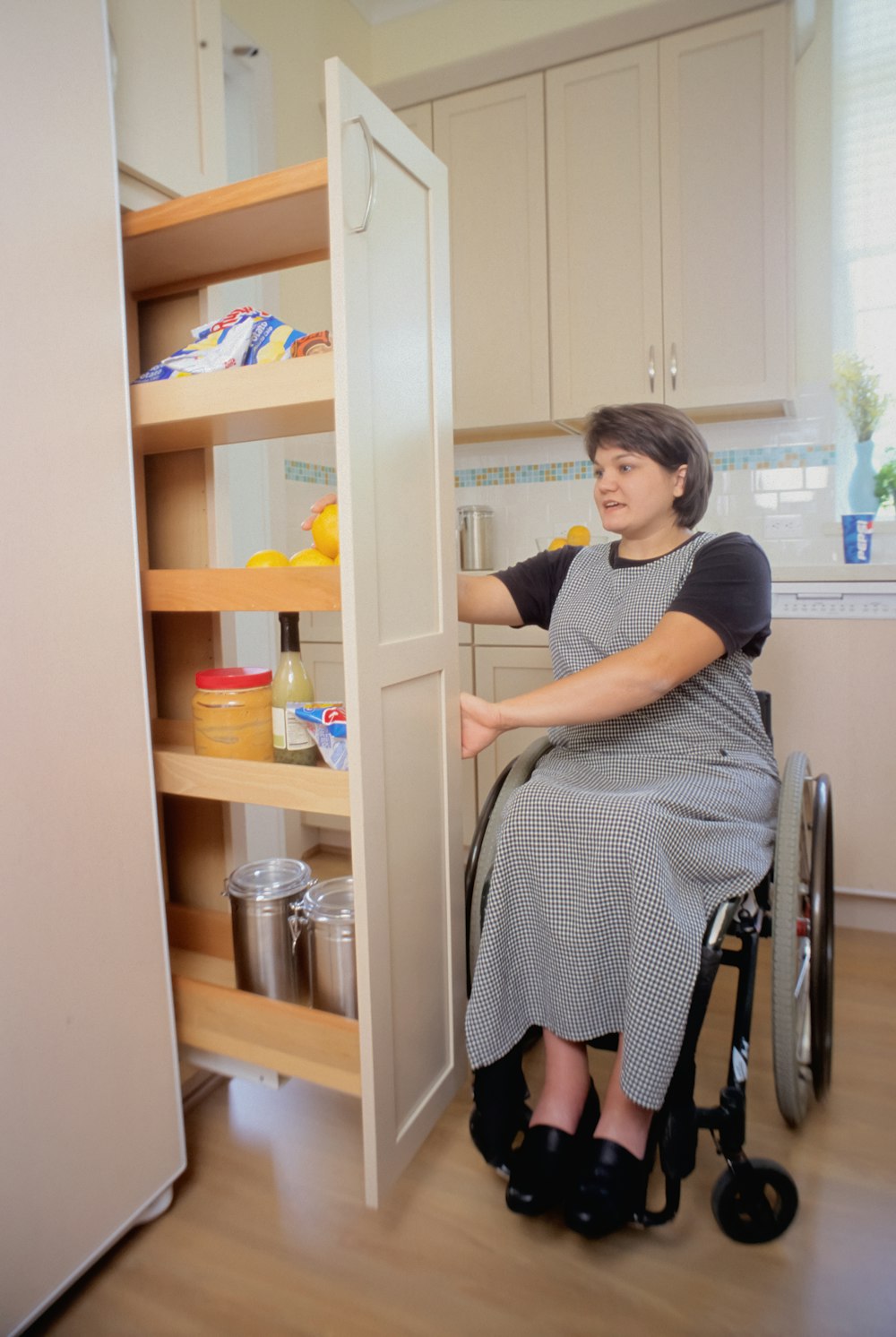 a woman in a wheel chair opening a cabinet