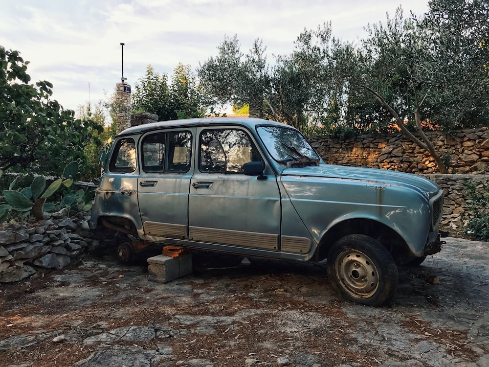 a small blue car parked next to a pile of rocks