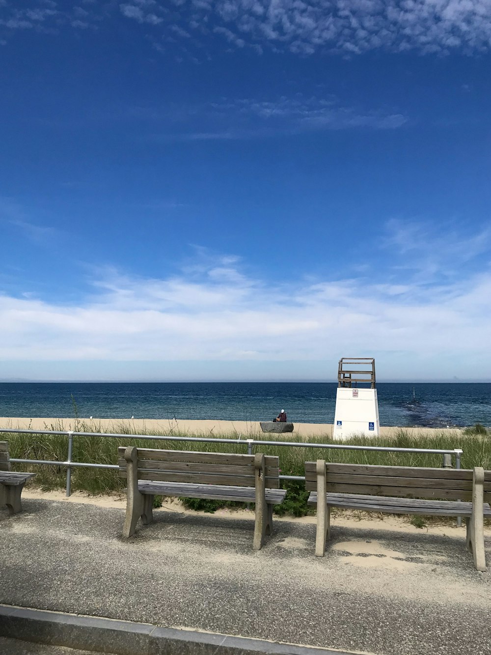 a couple of benches sitting on top of a sandy beach