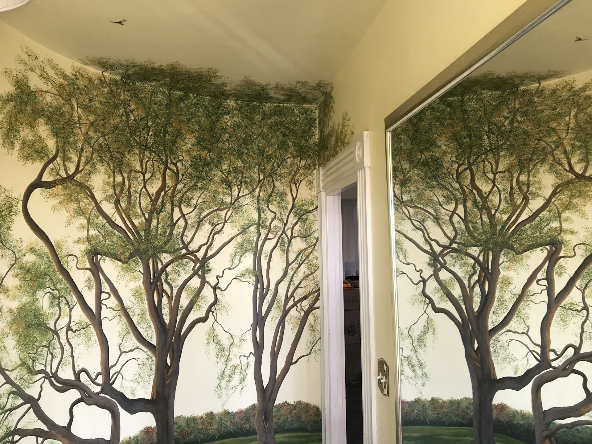 a bathroom with a mural of trees painted on the wall