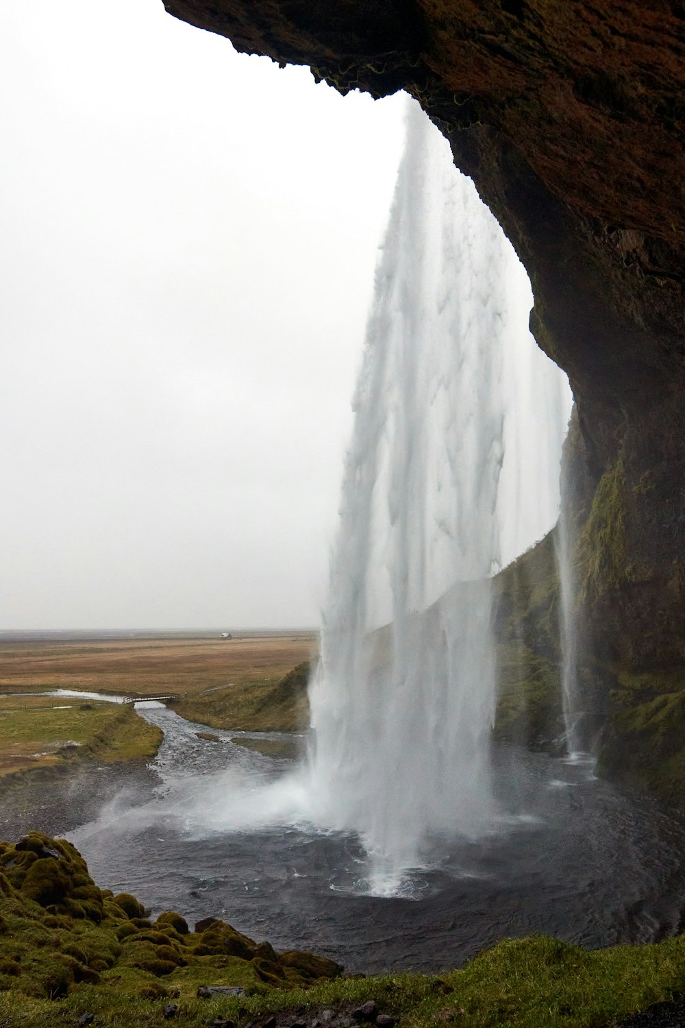 a large waterfall is coming out of the side of a cliff