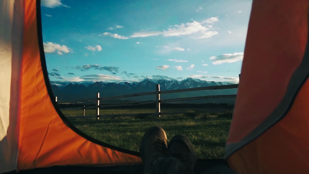 a person sitting in a tent with mountains in the background