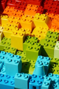 A collection of colorful building blocks arranged in a gradient pattern, showcasing a spectrum from red and orange at the top to green and blue at the bottom.