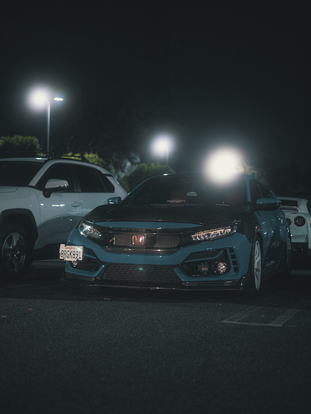 two cars parked in a parking lot at night