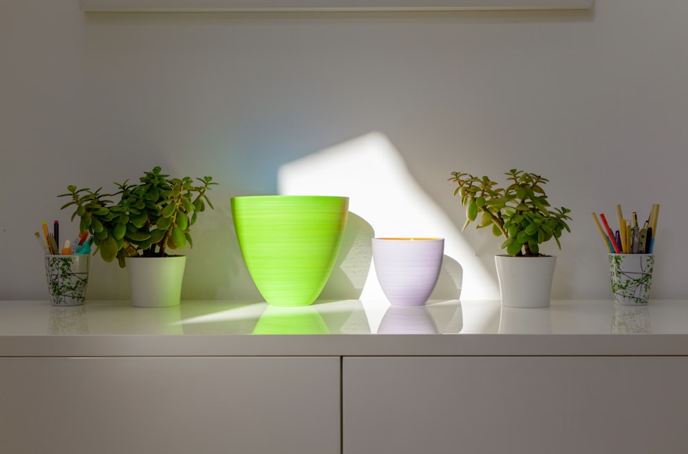 a white shelf topped with green and white vases